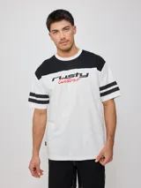 Remera blanca de hombre con corte negro en la parte superior del pecho y mangas cortas con tres rayas horizontales negras. Estampado frontal con el logo de Rusty en negro y la palabra 'Culture' en rojo.