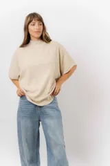 Sweater de tejido de punto color negro, con cuello semi alto y mangas cortas amplias. Presenta una silueta relajada y caída fluida.