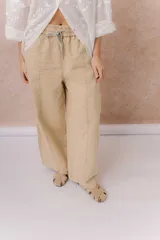 Pantalón de denim liviano color beige, de calce amplio y relajado con pierna recta. Cuenta con cintura elastizada, cordón regulable, bolsillos laterales y costuras delanteras verticales que estilizan la silueta.