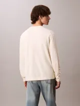Sweater Calvin Klein de corte relajado y color blanco, con cuello redondo, mangas largas y puños de canalé. Presenta un diseño gráfico de monograma CK en color block con bloques en verde, rosado y azul, acompañado del logotipo de la marca estampado en el pecho.