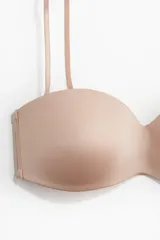 Soutien strapless de microfibra color beige con copas acolchadas, tirantes ajustables y removibles, y cierre de corchetes en la espalda.