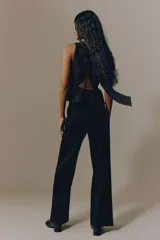 Pantalón sastrero de tiro alto y color negro, con piernas rectas, raya marcada al frente y bolsillos laterales al bies.