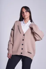Cárdigan color beige con botones negros, escote en V y detalles de costuras bordadas en negro.
