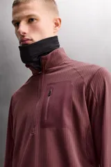 Sudadera técnica color vino tinto, de manga larga, con cuello subido y cierre frontal de cremallera. Presenta un bolsillo frontal con cierre de cremallera oculta en costura y detalle de logo estampado. El tejido tiene estructura waffle en el interior.