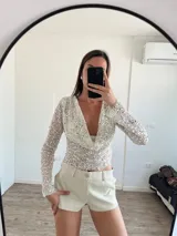 Top de fiesta color blanco, con escote drapeado y lentejuelas.