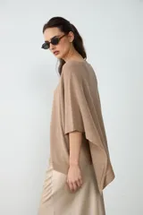 Poncho tejido de punto color tostado, con escote redondo y diseño amplio y asimétrico.