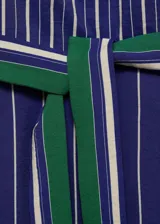 Mono largo de diseño recto y sin mangas, con cuello redondo y cierre de cremallera en la parte posterior. Presenta un estampado de rayas verticales en tonos azul y blanco, e incluye un cinturón desmontable con detalles en verde.