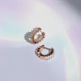 Par de aros tipo argolla oro rosa con cristales blancos en la superficie exterior e interior.