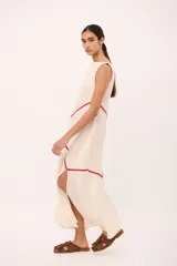 Vestido largo de lino marrón con cuello semi-bote, sin mangas y aberturas laterales en el bajo. Cuenta con detalles de líneas en color amarillo a contratono que recorren la prenda de forma diagonal.
