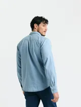 Camisa de denim de algodón con cuello clásico, cierre frontal con botones, bolsillo superior de parche y mangas largas con puños abotonados.