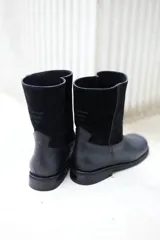 Botas de cuero vacuno color negro, con caña media, suela de caucho y taco bajo.