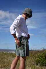 Short de baño verde con estampado de hojas y flores en tonos verde oscuro y marrón. Tiene bolsillos laterales y traseros, cintura elástica con cordón ajustable y corte clásico.