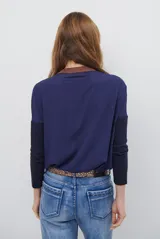 Remera de manga larga color bordó con cuello redondo en contraste color crema y costuras decorativas visibles en el ruedo y puños.