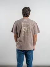Remera de corte oversize color marrón con efecto lavado, cuello redondo y estampa frontal con la frase 'URUGUAY noma!'.