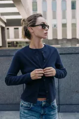 Chaqueta de punto color azul marino, con cuello redondo, manga larga y cierre frontal con botones. Los acabados son en rib a tono.