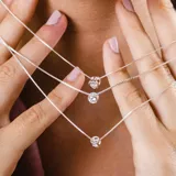 Conjunto de gargantilla y aros de plata con dije de punto de luz en circonia brillante. La cadena es fina y delicada, con un diseño minimalista y elegante.