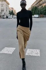 Pantalón tipo culotte de tiro alto, con pernera ancha y corta. Presenta detalles de botones dorados decorativos en la parte frontal y cierre lateral con cremallera oculta.