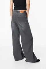 Jean de corte wide leg en color gris con efecto lavado, tiro medio y cierre frontal con botón y cremallera.