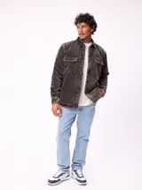 Sobrecamisa de pana color beige, con cierre frontal de botones a presión, dos bolsillos frontales con solapa y bolsillos laterales. Presenta cuello clásico y diseño acolchado con forro interior.