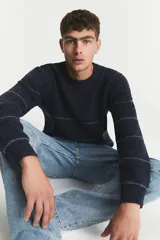 Sweater de punto grueso color azul marino con rayas horizontales finas en color gris claro. Cuello redondo y calce holgado.