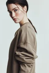 Buzo de tejido de algodón de peso medio, color marrón topo, con cuello redondo y hombros caídos. Presenta puños y bajo en punto acanalado.