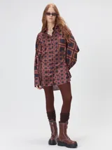 Camisa de seda con estampado geométrico de cuadrados en tonos rojizos y marrones. Presenta cuello camisero, cierre frontal con botones, bolsillo en el pecho y mangas largas con puños abotonados.