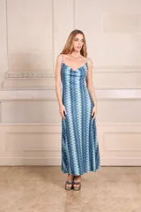 Vestido midi con estampado de ondas verticales en tonos fucsia, verde y plateado. Tiene breteles finos, escote drapeado y espalda baja.