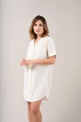 Camisa de dormir o camisón de manga corta, color champagne, con cuello en V y abotonadura frontal. Presenta un bolsillo de parche en el pecho.