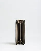 Billetera Flavia Fichero tipo organizador de color negro con textura granulada, cierre perimetral y logo metálico dorado en la parte frontal.