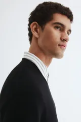 Buzo negro de punto acanalado, con cuello redondo y bajo recto.