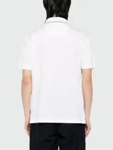 Polo de pique BOSS de color blanco, de manga corta, con cuello y puños acanalados que presentan detalles en contraste. Cuenta con cierre frontal de botones.