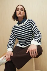 Sweater de punto con diseño de rayas horizontales en azul marino y blanco, con detalle de calados y cuello redondo. Presenta mangas largas con puños acanalados y un corte relajado.