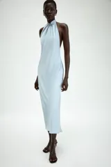 Vestido midi de satén color celeste, con cuello halter y detalle de lazada en la espalda descubierta.