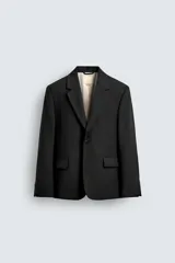 Blazer de corte relajado confeccionada en mezcla de lana y viscosa. Presenta cuello con solapas de muesca, cierre frontal de un botón, bolsillos con solapa en la cadera y abertura central en la espalda. Incluye forro interior a contraste y puños con botones.