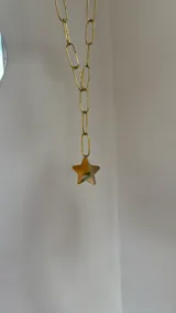 Collar de cadena de eslabones alargados en tono dorado con un dije colgante en forma de estrella de gran tamaño.