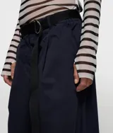 Pantalón de corte clásico y pernera muy ancha, color beige claro, con cintura elástica y cinturón de tela negro con logo bordado.