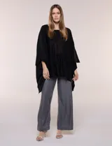 Poncho de calce holgado color marrón, confeccionado en tejido fino de punto suave, con cuello redondo y diseño de caídas laterales amplias de ruedo asimétrico.