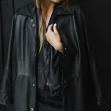 Chaqueta de cuero ovino negro, con cuello clásico y cierre frontal con botones a presión. Forrada.