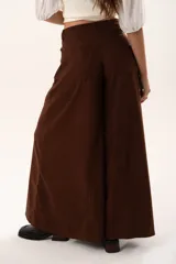 Pantalón de tiro medio con corte súper campana, confeccionado en tela de textura suave. Presenta cierre frontal con cremallera y botón, bolsillos delanteros y traseros, y costuras verticales que definen su estructura.