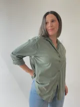 Camisa celeste de corte holgado, con cuello clásico, cierre frontal con botones, bolsillo en el pecho y mangas largas con puños abotonados.