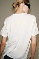 Camiseta oversize blanca de manga corta y cuello redondo, confeccionada en hilatura de algodón con detalle de texto estampado en contraste en el pecho.