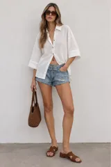 Camisa de lino blanca oversize, con cuello solapa, mangas anchas y cierre frontal con botones.