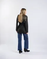 Campera tipo trench negra a la cadera, con solapa cruzada, doble botonadura frontal, hombreras y bolsillos delanteros con solapa.