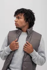 Chaleco puffer color gris topo, con cuello alto y cierre frontal.