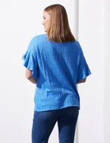 Blusa de mujer color azul vibrante con textura acanalada y pequeños patrones jacquard en relieve. Presenta un escote redondo y mangas cortas con vuelo.