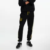 Pantalón de jogging negro con puños elásticos, cordón ajustable en la cintura, escudo del Club Atlético Peñarol bordado en amarillo y franjas laterales amarillas y grises.
