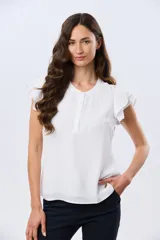 Blusa blanca sin mangas con volados en los hombros, cuello redondo con aberturas y cierre frontal parcial con botones.