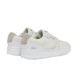 Championes Lacoste modelo L004, de diseño urbano en color blanco con detalles en gris claro. Presentan una silueta de perfil bajo con paneles de lona y refuerzos de gamuza en la puntera y el talón. Incluyen el icónico logo del cocodrilo metálico en el lateral del talón y una suela de goma vulcanizada.