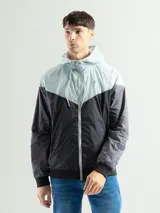 Campera deportiva negra de nylon impermeable con capucha y cierre frontal. Presenta puños y cintura elásticos de tejido acanalado. Tiene un pequeño logo blanco en el pecho.