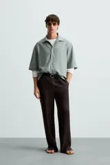 Camisa de corte relajado confeccionada en tejido mezcla de lyocell, con cuello solapa, manga corta y cierre frontal con botonadura oculta.